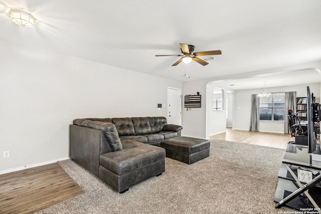 living room with ceiling fan with notable chandelier and light hardwood / wood-style flooring