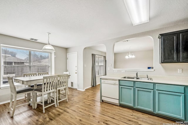 kitchen with pendant lighting, sink, green cabinets, white dishwasher, and light hardwood / wood-style floors