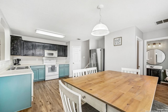 kitchen featuring pendant lighting, sink, white appliances, blue cabinetry, and light wood-type flooring