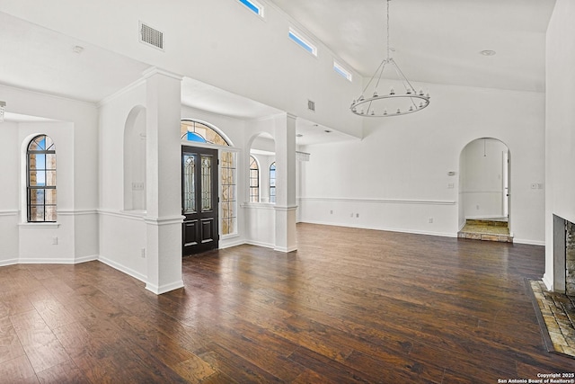 interior space featuring a towering ceiling, a notable chandelier, and dark hardwood / wood-style flooring