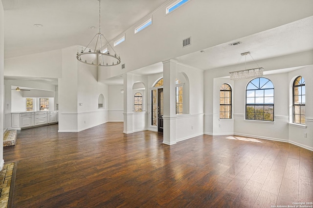 unfurnished living room featuring a high ceiling, dark hardwood / wood-style floors, and ceiling fan with notable chandelier