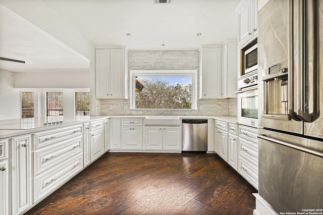 kitchen featuring white cabinetry, dark wood-type flooring, kitchen peninsula, and appliances with stainless steel finishes