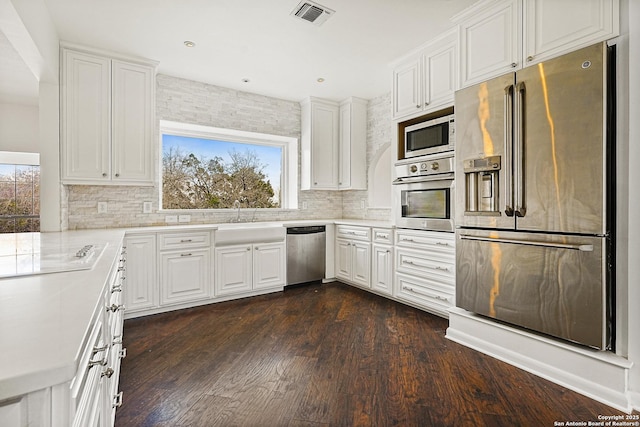 kitchen featuring sink, dark hardwood / wood-style flooring, white cabinets, stainless steel appliances, and backsplash