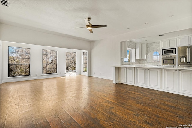 unfurnished living room featuring sink, hardwood / wood-style flooring, and ceiling fan