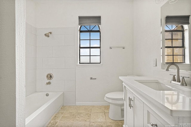 full bathroom featuring vanity, tiled shower / bath, and toilet