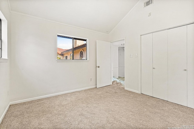 unfurnished bedroom featuring ornamental molding, lofted ceiling, light colored carpet, and a closet