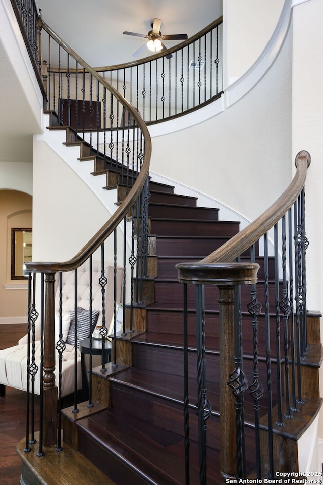 staircase featuring a high ceiling, hardwood / wood-style floors, and ceiling fan