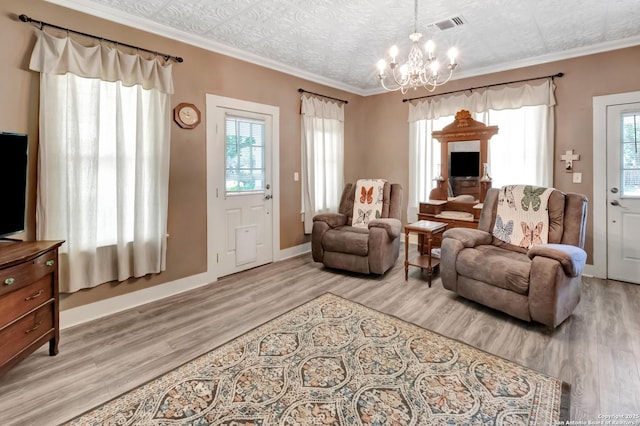 living area with ornamental molding, a chandelier, and light hardwood / wood-style flooring