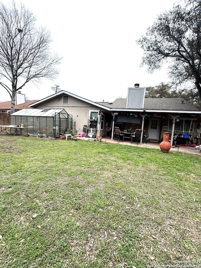 rear view of house featuring a patio, an outdoor structure, and a yard