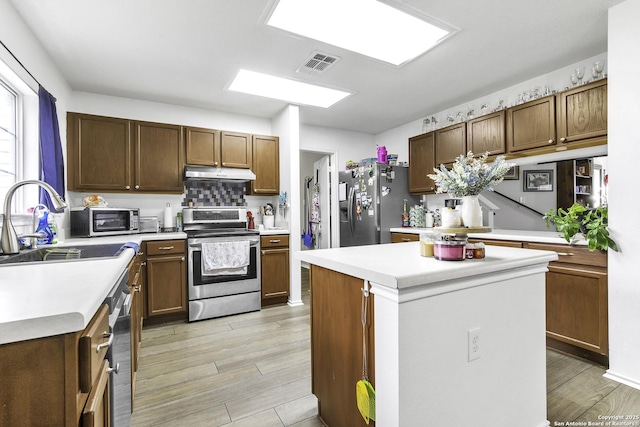 kitchen featuring sink, light wood-type flooring, a center island, and appliances with stainless steel finishes