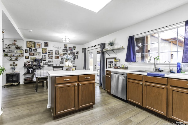 kitchen featuring stainless steel dishwasher, wood-type flooring, a center island, and sink