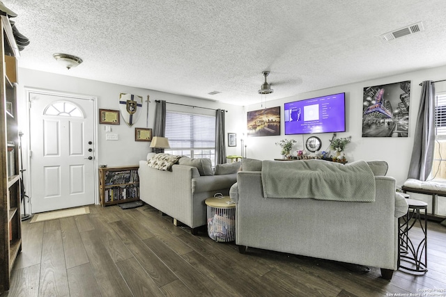 living room with dark wood-type flooring, a textured ceiling, and ceiling fan