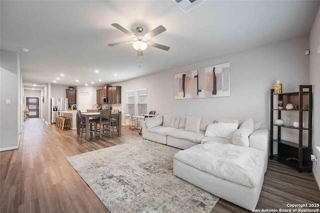 living room with dark hardwood / wood-style flooring and ceiling fan