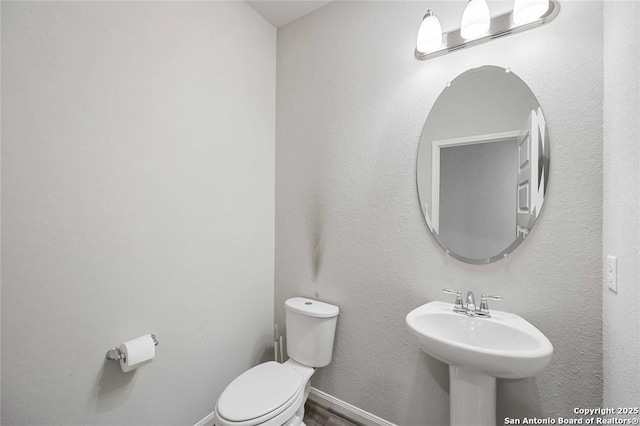 bathroom featuring toilet, sink, and hardwood / wood-style floors