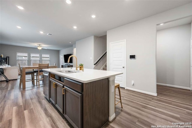 kitchen featuring dark brown cabinetry, sink, dishwasher, an island with sink, and light hardwood / wood-style floors