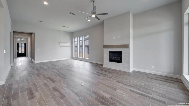 109 Barton Crk, Boerne, TX 78006 - unfurnished living room featuring ceiling fan, baseboards, wood finished floors, a glass covered fireplace, and recessed lighting