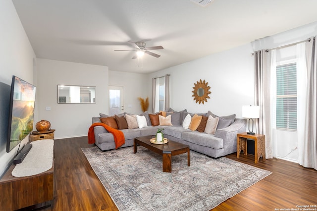 living room featuring dark wood-type flooring and ceiling fan