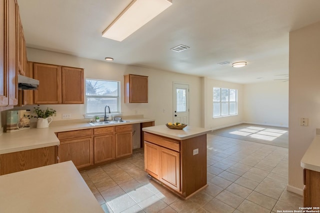 kitchen with light tile patterned flooring, a center island, and sink