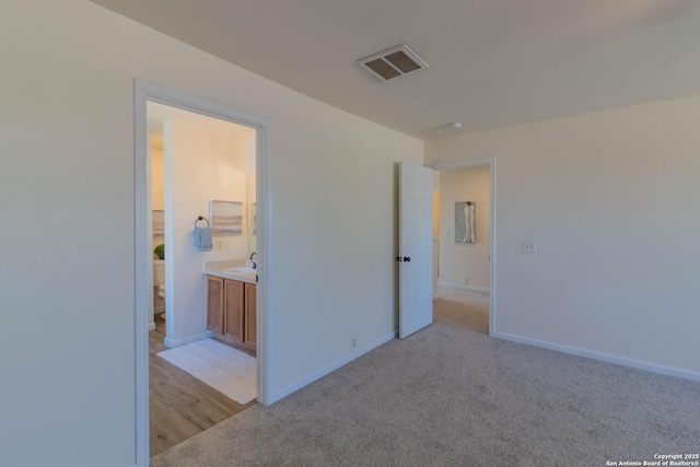 unfurnished bedroom featuring light colored carpet and connected bathroom