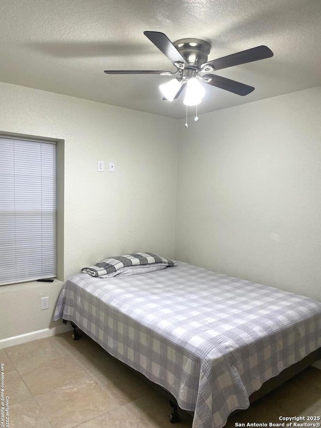 tiled bedroom featuring ceiling fan and a textured ceiling