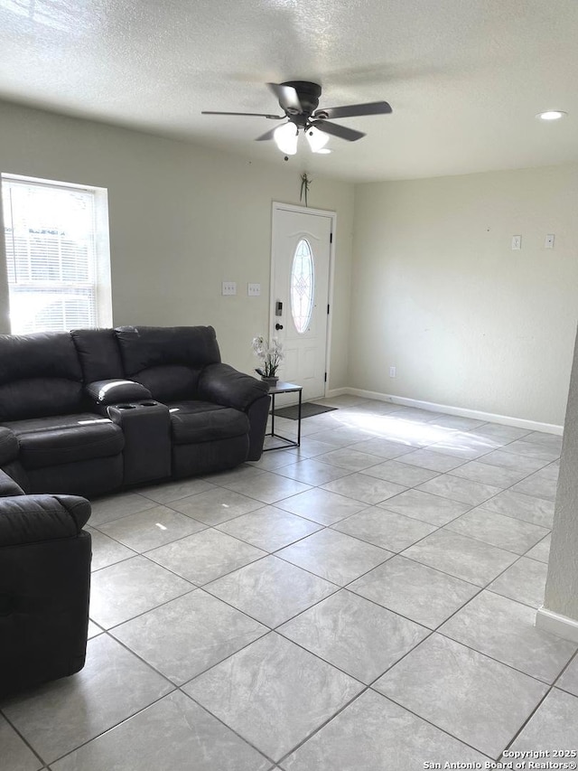 living room featuring ceiling fan, a textured ceiling, and light tile patterned floors