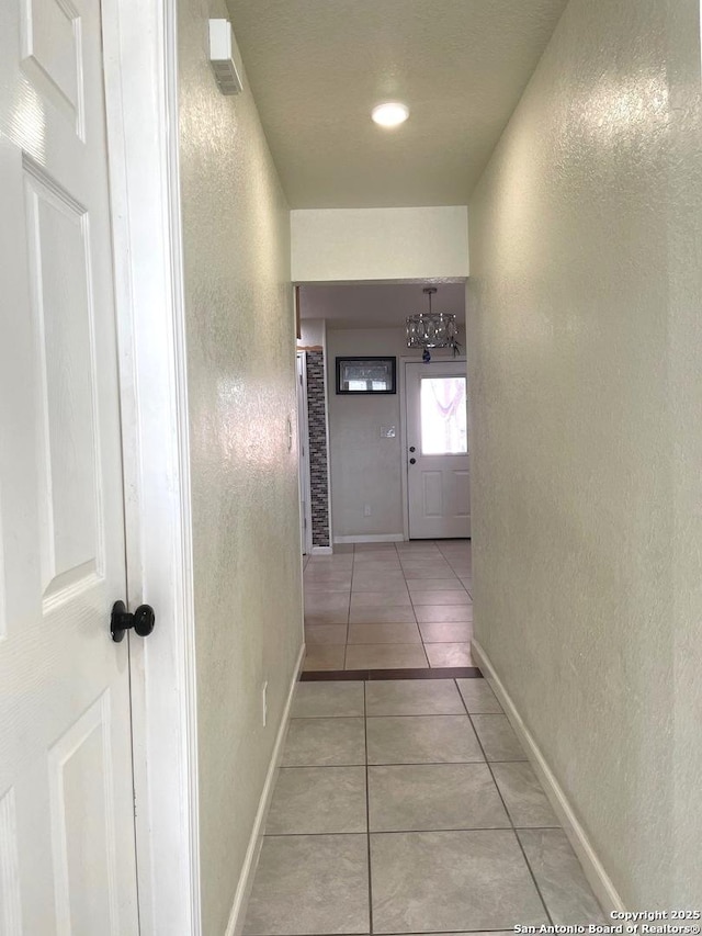 corridor featuring a notable chandelier and light tile patterned flooring