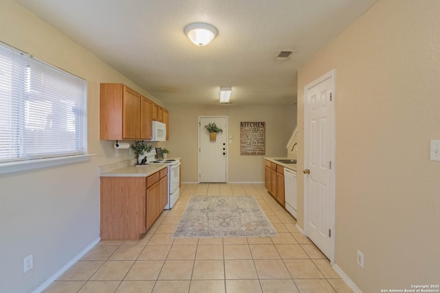 kitchen featuring light tile patterned flooring, sink, and white appliances