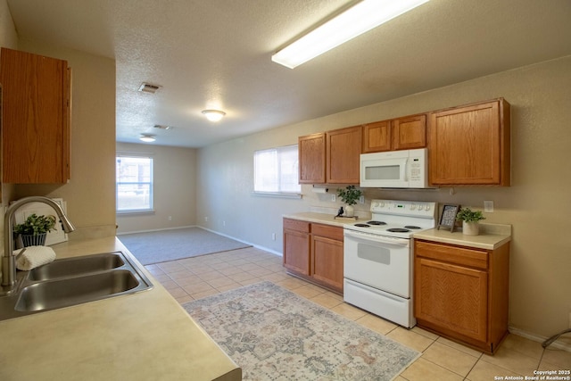 kitchen with white appliances, sink, a textured ceiling, and light tile patterned floors