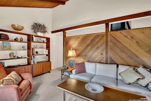 carpeted living room with wooden walls, wood ceiling, and beam ceiling