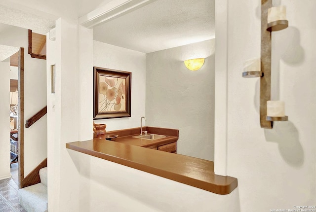 bar featuring sink and a textured ceiling