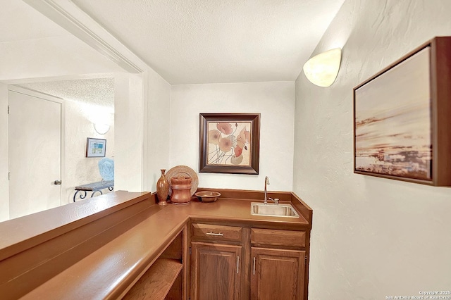 bar with sink and a textured ceiling