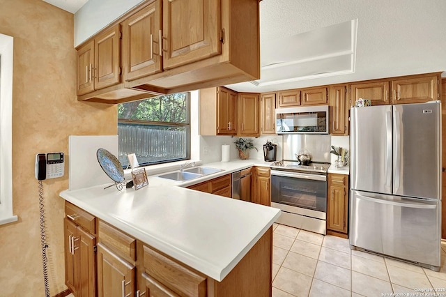 kitchen with light tile patterned flooring, appliances with stainless steel finishes, sink, and kitchen peninsula