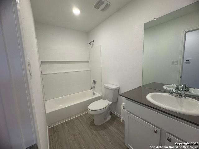 full bathroom with shower / tub combination, wood-type flooring, vanity, and toilet