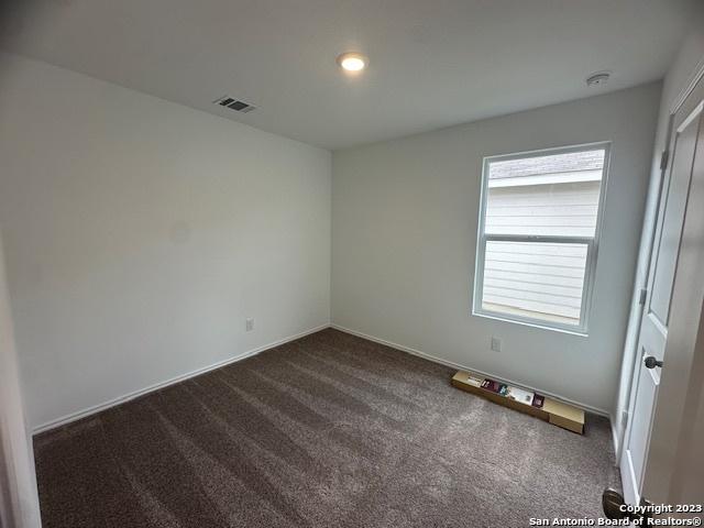 unfurnished room featuring dark colored carpet