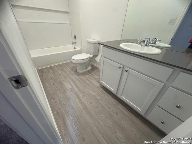 full bathroom featuring vanity, hardwood / wood-style flooring, shower / bathtub combination, and toilet