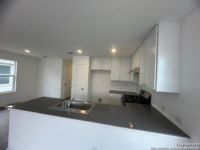 kitchen featuring white cabinetry, kitchen peninsula, sink, and stainless steel gas stove