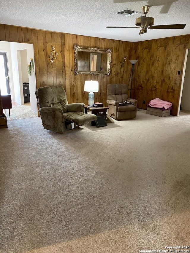 living room with ceiling fan, carpet floors, and a textured ceiling