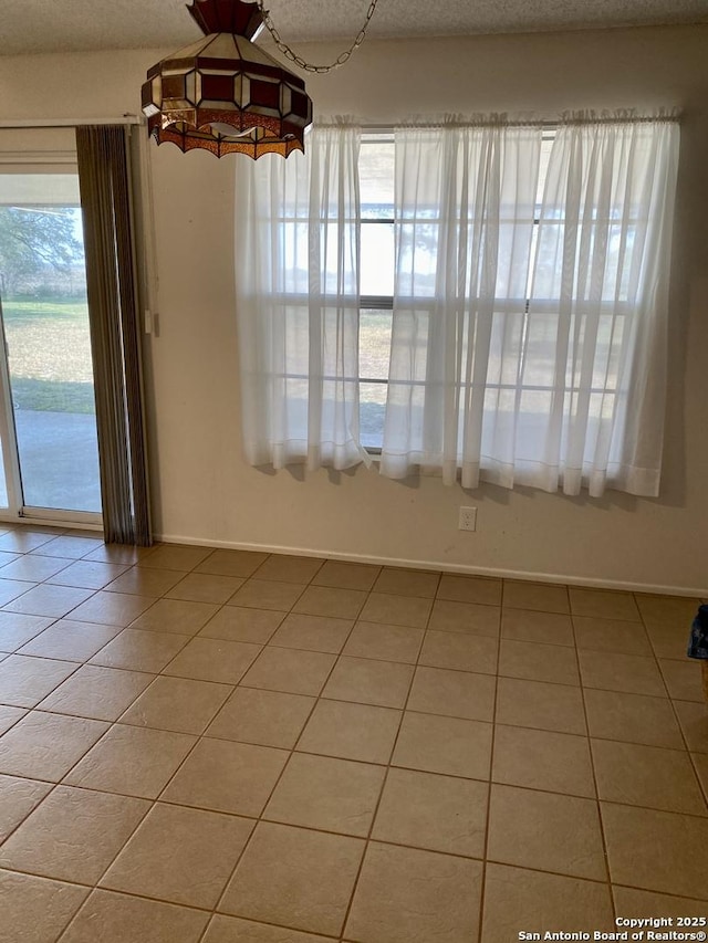 unfurnished dining area featuring tile patterned floors and a textured ceiling