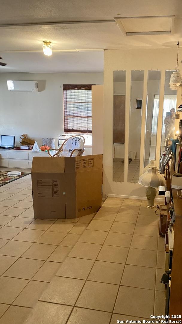 interior space featuring light tile patterned floors and a wall unit AC