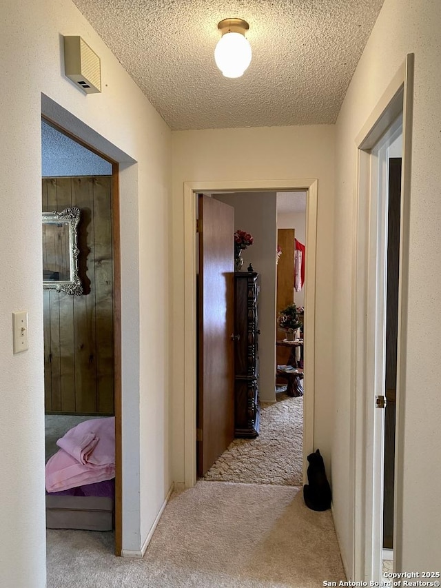 hall with carpet flooring and a textured ceiling