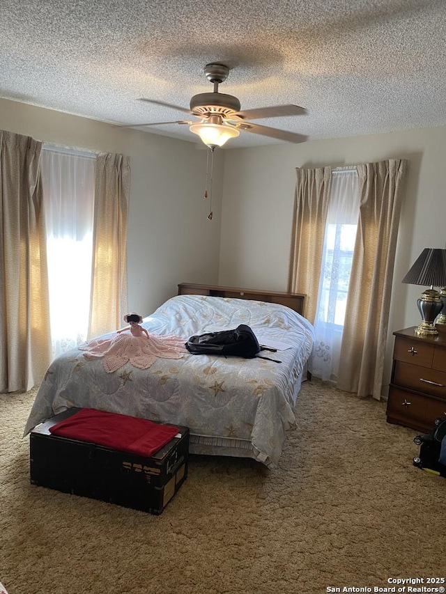 carpeted bedroom featuring ceiling fan and a textured ceiling