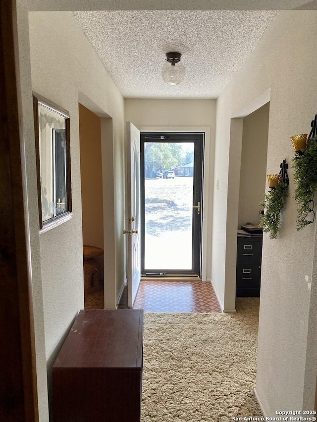 doorway to outside featuring carpet and a textured ceiling