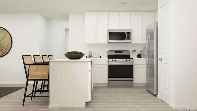 kitchen featuring white cabinetry, stainless steel appliances, a kitchen bar, and light hardwood / wood-style flooring