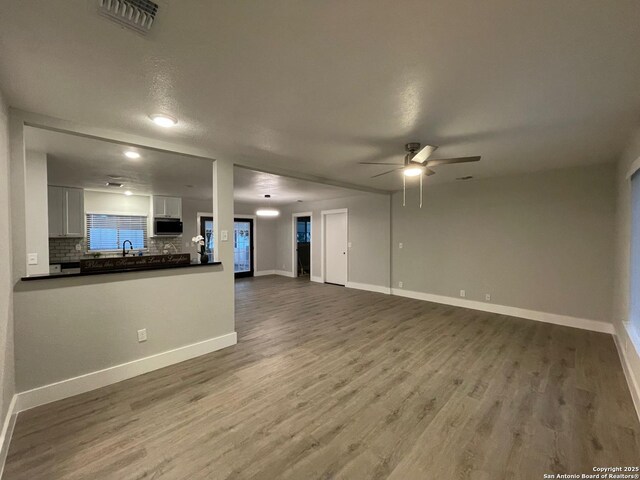 unfurnished living room with sink, wood-type flooring, and ceiling fan