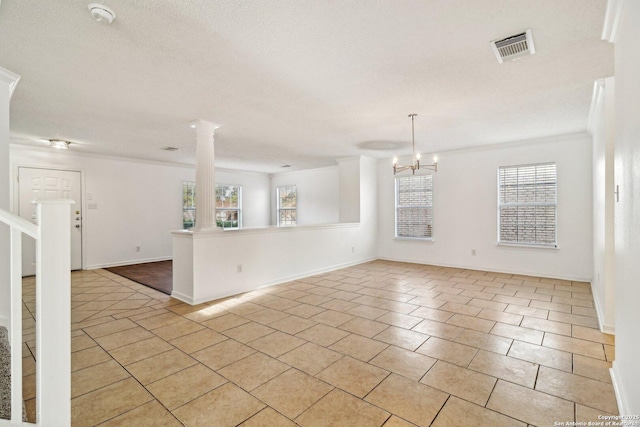 tiled spare room with decorative columns, a textured ceiling, and a notable chandelier