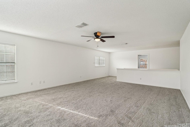 carpeted spare room featuring ceiling fan and a textured ceiling