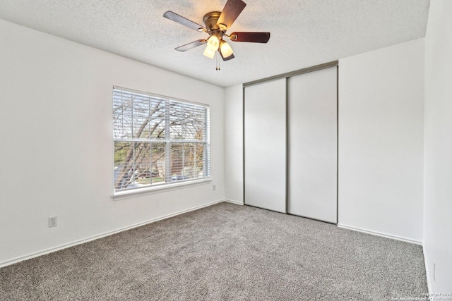 unfurnished bedroom featuring ceiling fan, a closet, carpet floors, and a textured ceiling