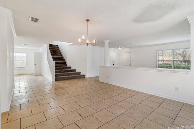 unfurnished room with decorative columns, an inviting chandelier, a textured ceiling, and light tile patterned floors