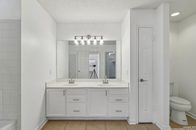 bathroom featuring vanity, tile patterned flooring, a textured ceiling, and toilet