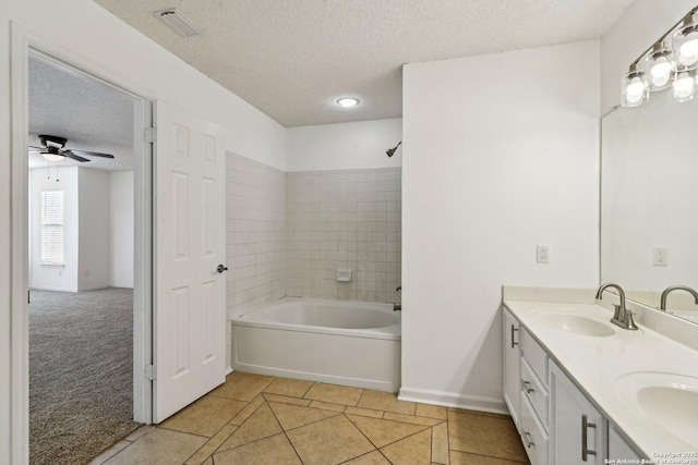 bathroom with tiled shower / bath, vanity, ceiling fan, tile patterned floors, and a textured ceiling